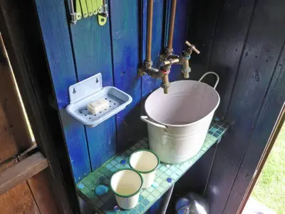 a bathroom with a bucket and a sink at Cwt Cwtshlyd in Tregaron