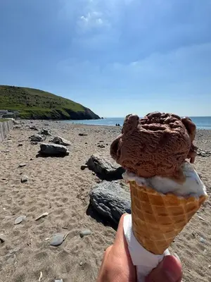 a person holding an ice cream cone on a beach at Welsh Seaview Stay 3 bed caravan by pool, club and beach in Aberystwyth