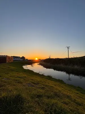 a sunset over a river in a field at Welsh Seaview Stay 3 bed caravan by pool, club and beach in Aberystwyth