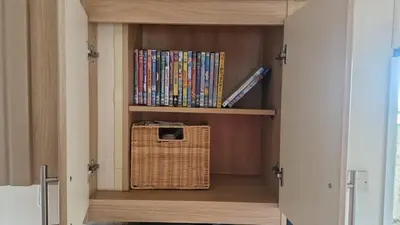 a room with a book shelf with dvds at Welsh Seaview Stay 3 bed caravan by pool, club and beach in Aberystwyth