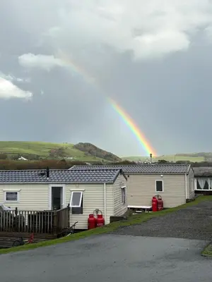 a rainbow in the sky over a house at Welsh Seaview Stay 3 bed caravan by pool, club and beach in Aberystwyth