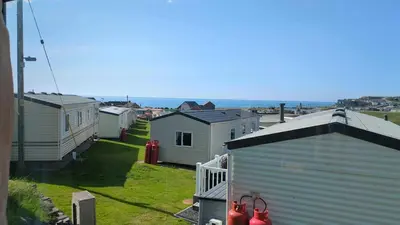 a row of houses with the ocean in the background at Welsh Seaview Stay 3 bed caravan by pool, club and beach in Aberystwyth
