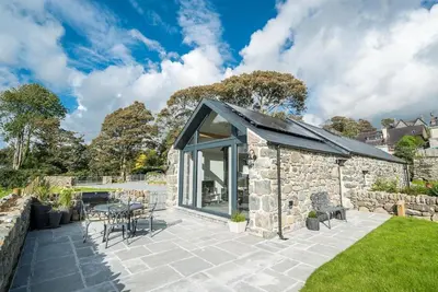 a stone house with a glass roof and a patio at Y-Ddol in Dyffryn