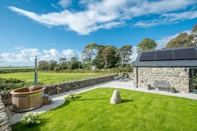 a stone house with a garden and a stone wall at Y-Ddol in Dyffryn