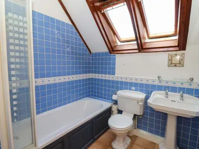 a blue tiled bathroom with a toilet and a sink at Gaer Hall in Welshpool