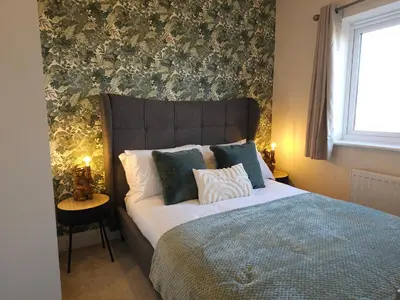 a bedroom with a large bed with blue and white pillows at STYLISH & SPACIOUS 4 BEDROOM HOUSE - FREE DRIVEWAY PARKiNG in Shrewsbury
