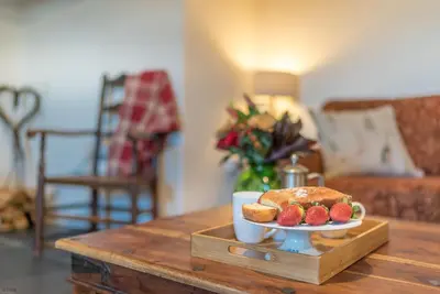 a coffee table with a plate of bread and strawberries at Y-Felin in Dyffryn