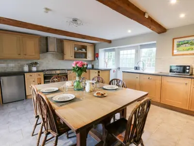 a kitchen with a wooden table and chairs at Secret Garden Cottage in Lampeter