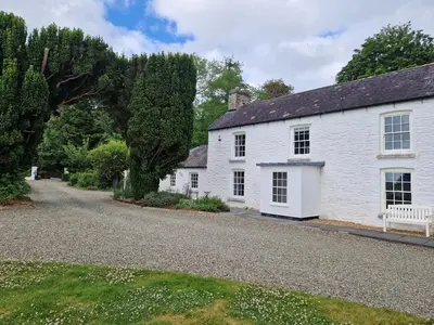 a white house with a gravel driveway at Secret Garden Cottage in Lampeter