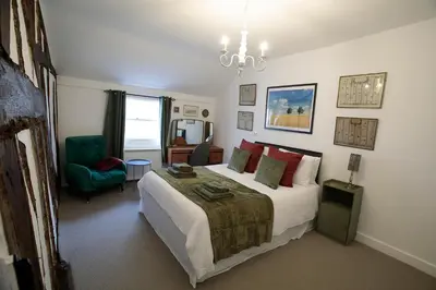 a bedroom with a bed and a green chair at Pepper House Rooms - shared facilities - pet friendly in Ludlow