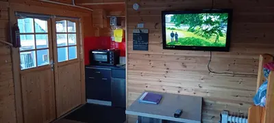 a room with a television on a wall with a kitchen at Alpaca Hideaway in Newtown