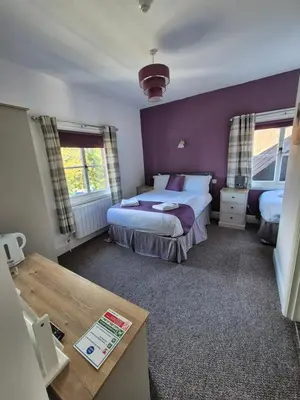 a bedroom with a bed and a purple wall at The Stokesay Inn in Craven Arms
