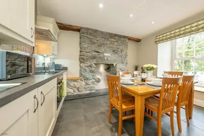 a kitchen with a table and chairs and a stone fireplace at Faeldre in Dyffryn