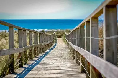 a wooden bridge over the ocean on the beach at Faeldre in Dyffryn