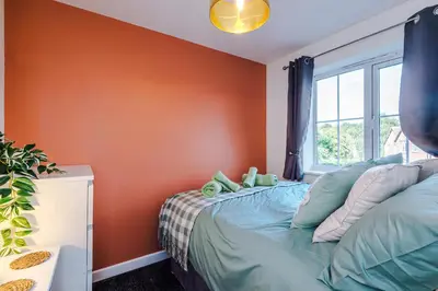 a bedroom with an orange wall and a bed at Long Term Stay 3 Bed 1 Bath & Parking Shropshire in Oswestry