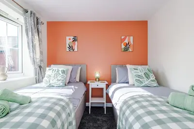 two beds in a room with orange walls at Long Term Stay 3 Bed 1 Bath & Parking Shropshire in Oswestry