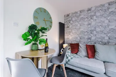 a living room with a couch and a table and a clock at Long Term Stay 3 Bed 1 Bath & Parking Shropshire in Oswestry