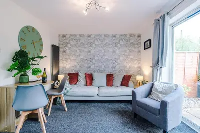 a living room with a couch and a table and a clock at Long Term Stay 3 Bed 1 Bath & Parking Shropshire in Oswestry