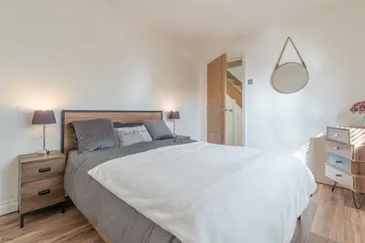 a white bedroom with a large bed and a mirror at Ty-Mari in Harlech