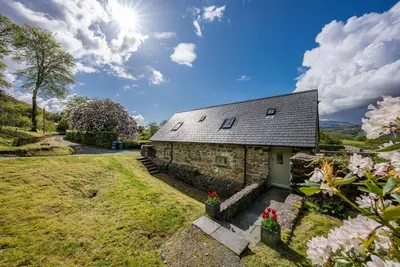 an external view of a stone cottage with flowers at Coed-Stable in Dolgellau