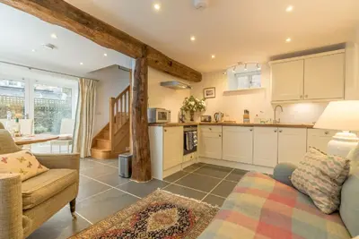 a living room with a couch and a kitchen at Coed-Stable in Dolgellau