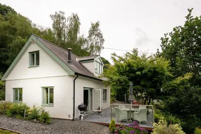 a white house with a deck in the yard at Erw-Fair in Arthog