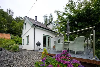 a house with a deck with two chairs and a grill at Erw-Fair in Arthog