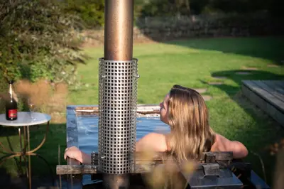 a woman is sitting in a jacuzzi tub at Saffir Luxury Eco Lodge, log-fired bath & views in Dihewid