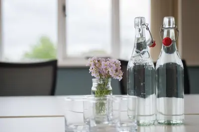 two bottles and glasses on a table with flowers at Saffir Luxury Eco Lodge, log-fired bath & views in Dihewid