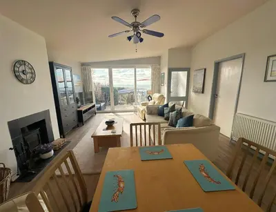 a living room with a table and a ceiling fan at Terrace by the Tide in Aberdyfi