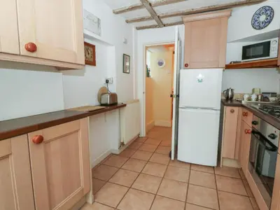 a kitchen with wooden cabinets and a white refrigerator at 6 Church Lane in Llanidloes
