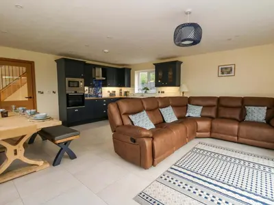 a living room with a brown leather couch and a table at Beudy in Aberystwyth