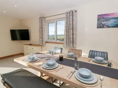 a dining room with a wooden table and chairs at Beudy in Aberystwyth