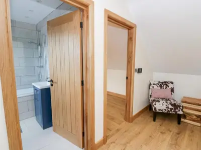 a bathroom with a wooden door and a chair at Beudy in Aberystwyth