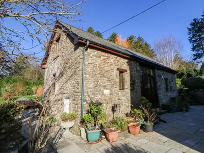 an old stone building with plants in pots at Maggie's Barn in Brecon