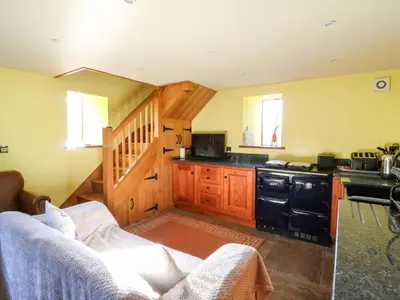 a living room with a couch and a kitchen at Maggie's Barn in Brecon