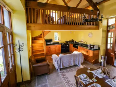 a kitchen with wooden cabinets and a table in a room at Maggie's Barn in Brecon