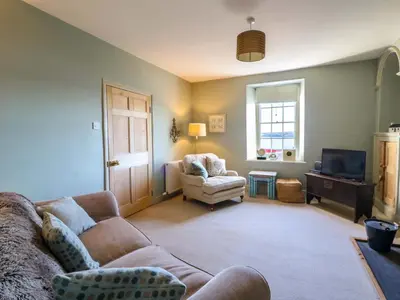 a living room with a couch and a chair and a television at Zenobia in New Quay