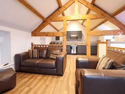 a living room with leather furniture and wooden ceilings at Clegir Bach in Corwen