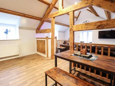 a large living room with a table and a tv at Clegir Bach in Corwen
