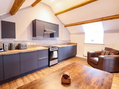 a kitchen with blue cabinets and a wooden table at Clegir Bach in Corwen