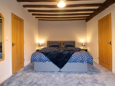 a bedroom with a bed with a blue and white comforter at Clegir Bach in Corwen