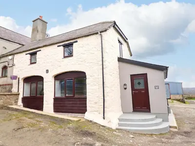 an old white brick building with a red door at Clegir Bach in Corwen