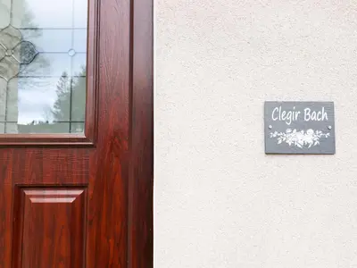 a wooden door with a sign that reads clerk bush at Clegir Bach in Corwen