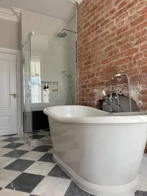 a white bath tub in a bathroom with a brick wall at Luxury Apartment in Shropshire sleeps 6 in Shrewsbury