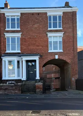 a red brick house with a black door and an archway at Luxury Apartment in Shropshire sleeps 6 in Shrewsbury