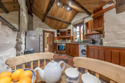 a kitchen with wooden cabinets and a table with fruit at Hywel-Sele-Lodge in Llanfachreth