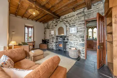 a living room with a couch and a stone fireplace at Hywel-Sele-Lodge in Llanfachreth