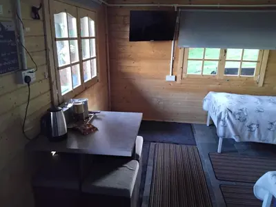 a room with a table and a bed in a wooden room at Moonlight View in Newtown