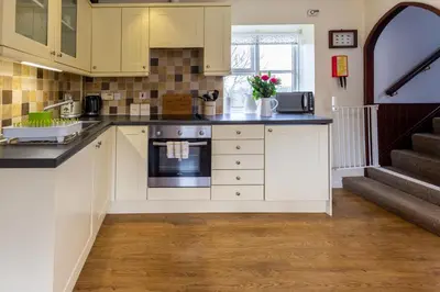 a kitchen with white cabinets and a counter top at Y Beudy
